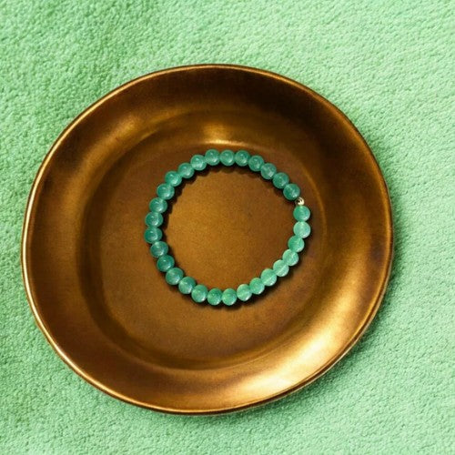Green aventurine bead bracelet on bronze plate symbolizing optimism and courage