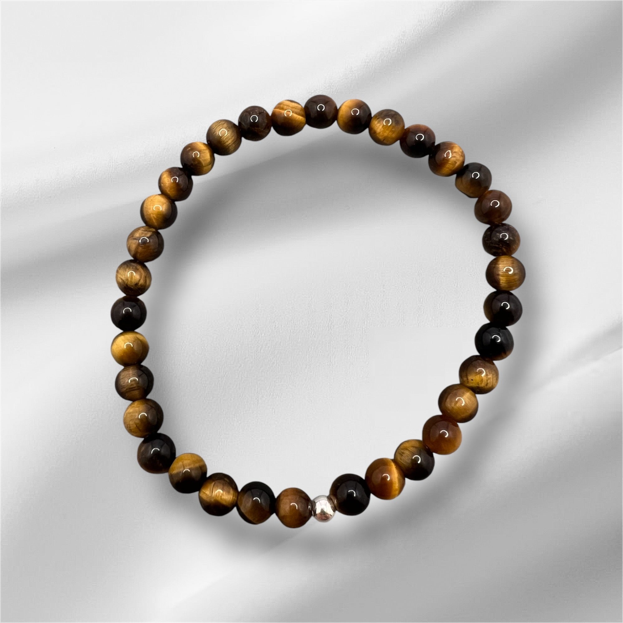 Tigerauge Armband aus handgefertigten gold-braunen Edelsteinperlen mit elastischem Band und silberner Verschlussperle, symbolisiert Mut und Willenskraft.