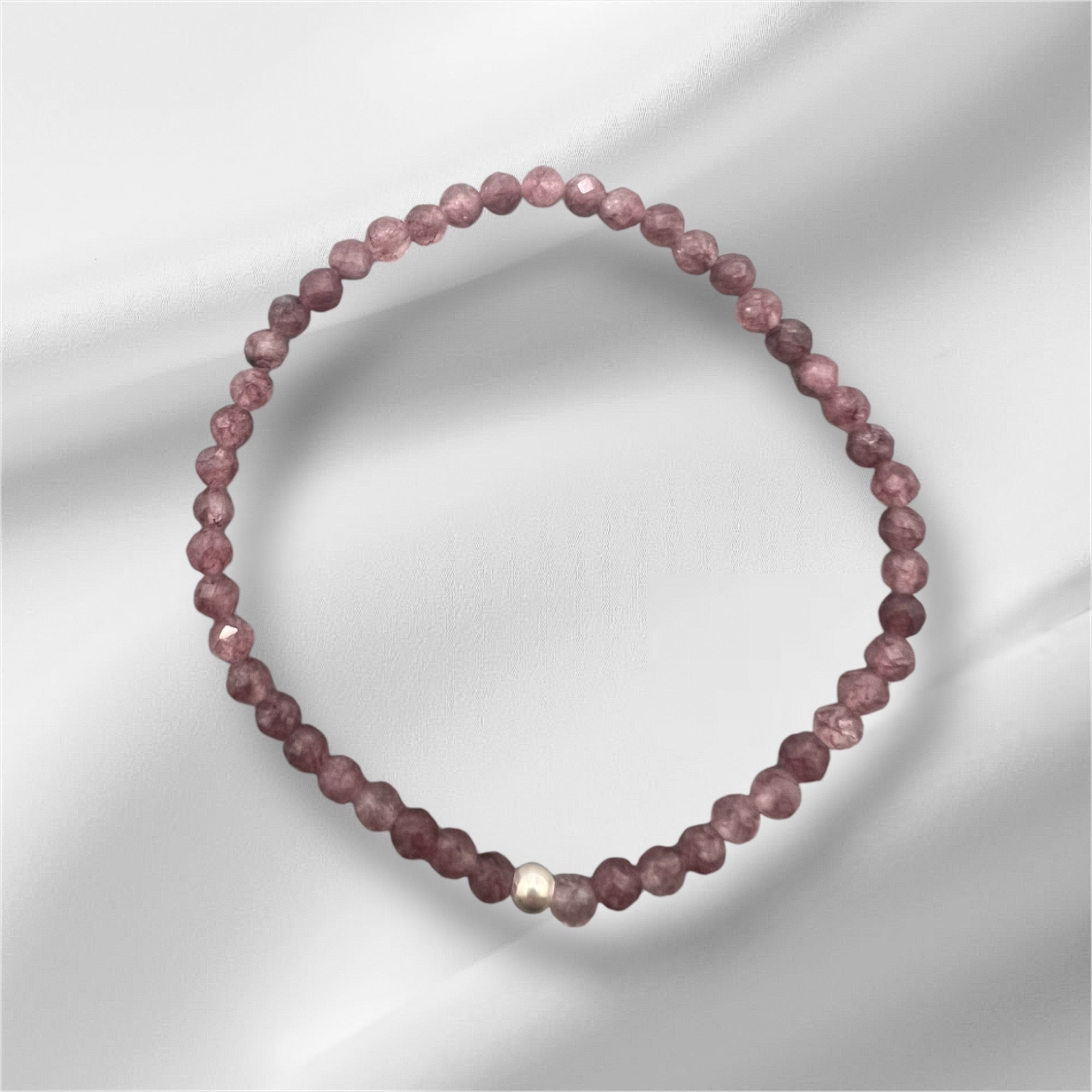 Nahaufnahme eines facettierten Lepidolith Armbands mit goldener Detailperle