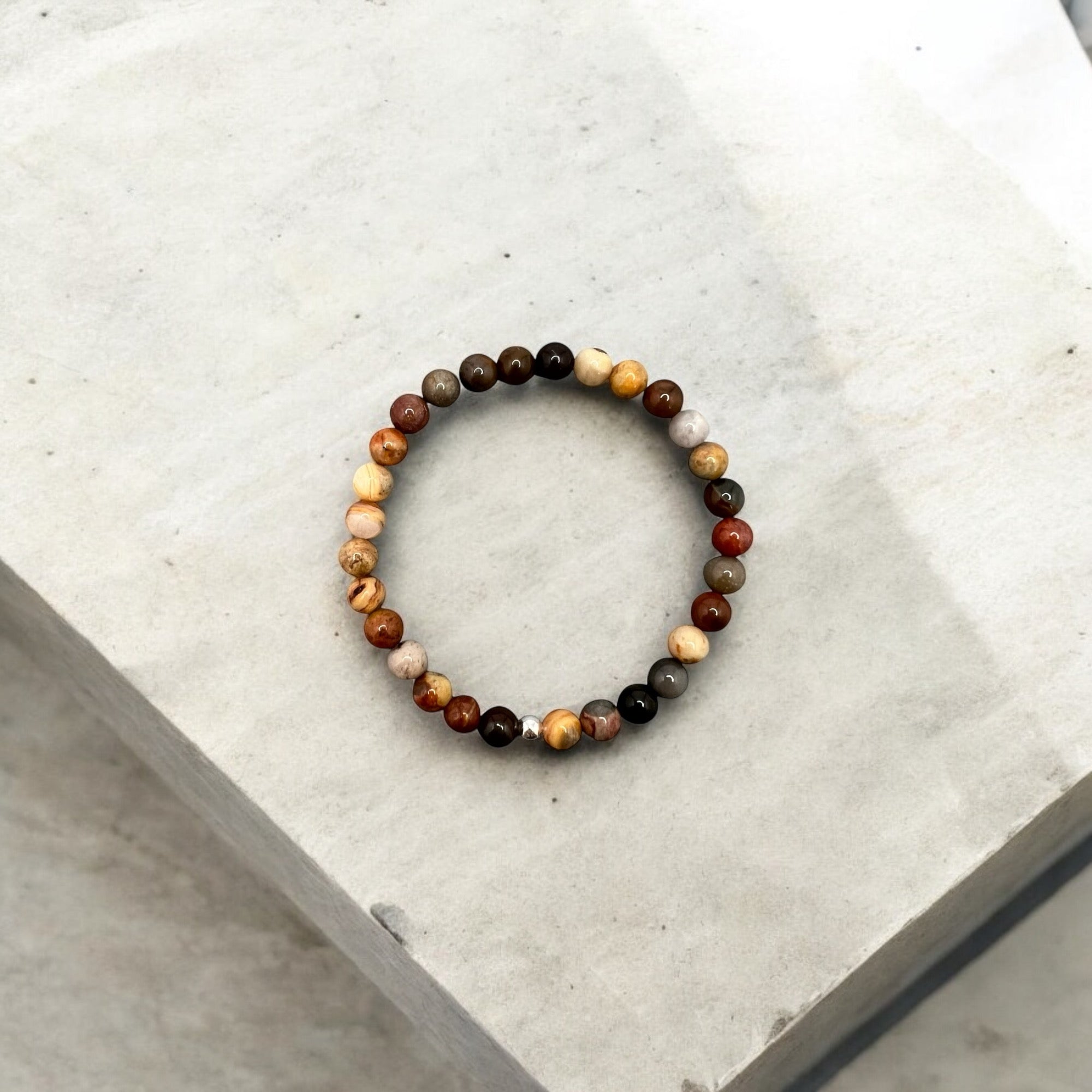 Round 6mm multi-colored natural jasper bead bracelet symbolizing strength, patience, and protection on a neutral background