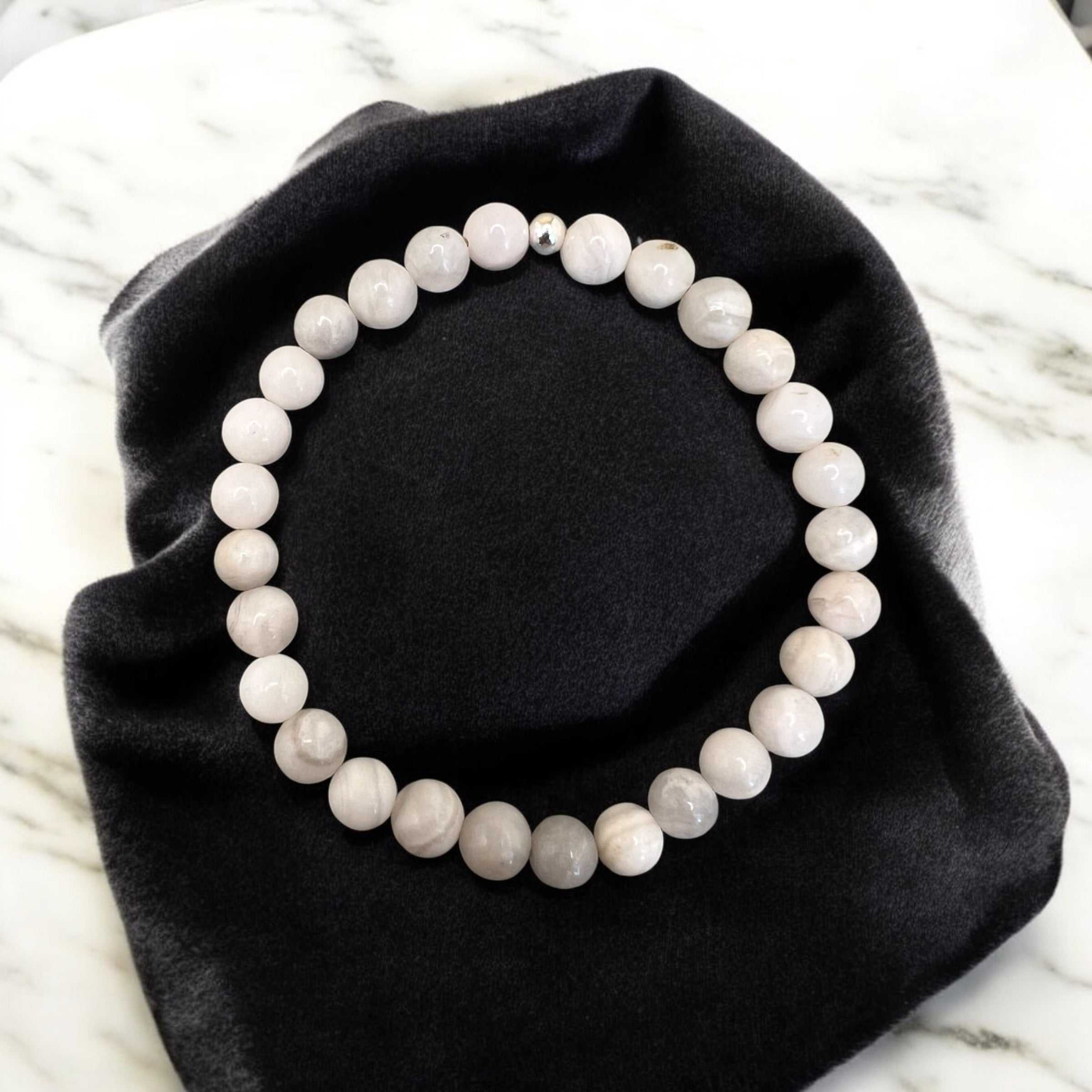 White Achat Armband made of 6mm round stones symbolizing purity and inner calm placed on a black cloth
