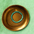 Green aventurine bead bracelet on bronze plate symbolizing optimism and courage