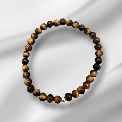 Tigerauge Armband aus handgefertigten gold-braunen Edelsteinperlen mit elastischem Band und silberner Verschlussperle, symbolisiert Mut und Willenskraft.