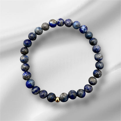 Handgefertigtes Lapislazuli Armband mit blauen Edelsteinperlen und goldener Verschlussperle, symbolisiert Weisheit und innere Wahrheit.