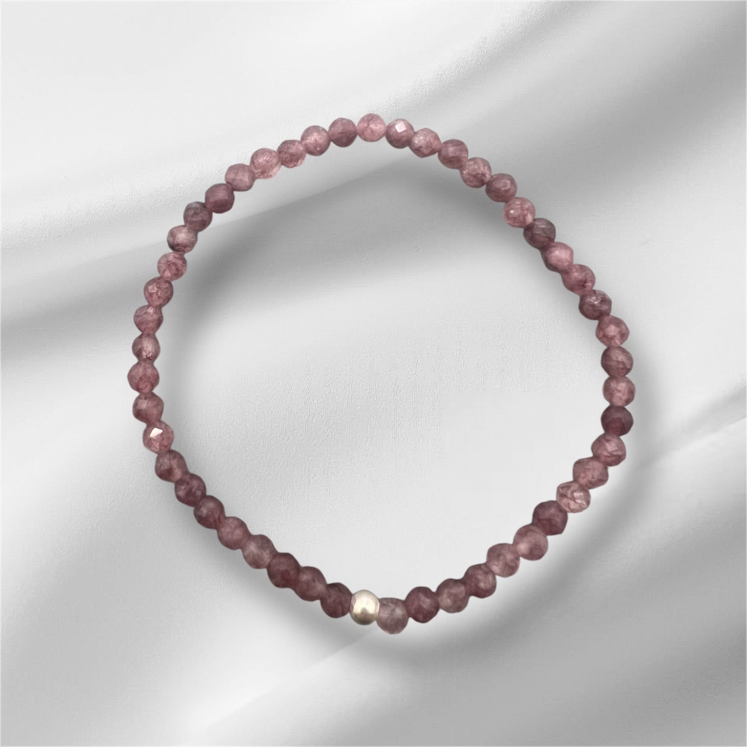 Nahaufnahme eines facettierten Lepidolith Armbands mit goldener Detailperle