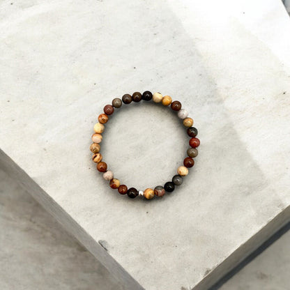 Round 6mm multi-colored natural jasper bead bracelet symbolizing strength, patience, and protection on a neutral background