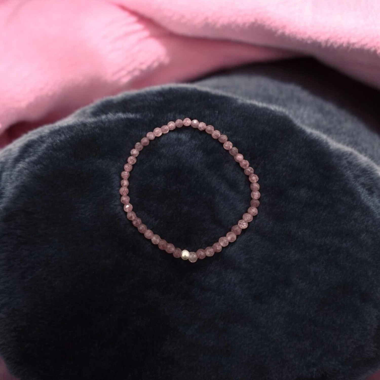 Faceted 4mm Lepidolith Armband with light violet beads symbolizing inner peace and protection, displayed on dark fabric background