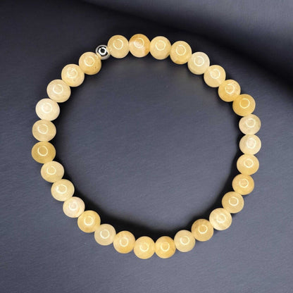 Handcrafted yellow chalcedony bracelet for optimism and inner calm, featuring elegant gemstone beads on a dark background.