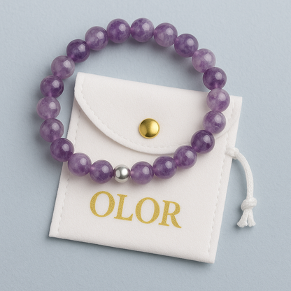 Amethyst Armband mit lila Edelsteinperlen und silberner Verschlussperle auf weißem Schmuckbeutel, handgefertigt für Schutz und innere Ruhe.