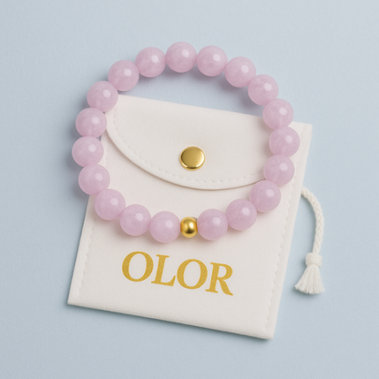 Kunzit Armband with 6mm round pink beads and gold accent on elastic band, displayed on white OLOR pouch