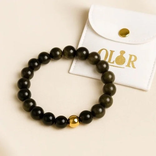 Handcrafted Gold Obsidian Armband with black and gold beads for protection and grounding, accompanied by a white OLOR pouch.